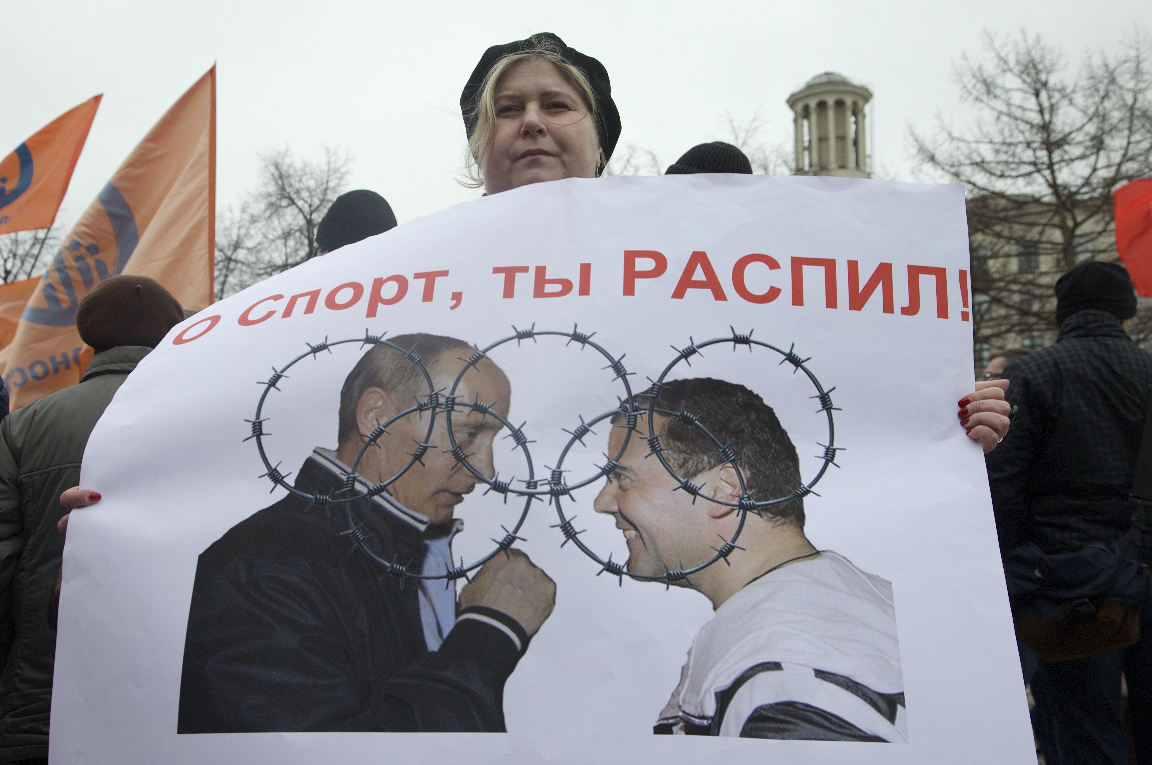 6 April 2013, Russia. During a rally in Moscow, a demonstrator holds an anti-corruption poster showing Russian President Vladimir Putin and Prime Minister Dimitry Medvedev overlayed with the Olympic rings in barbed wire.