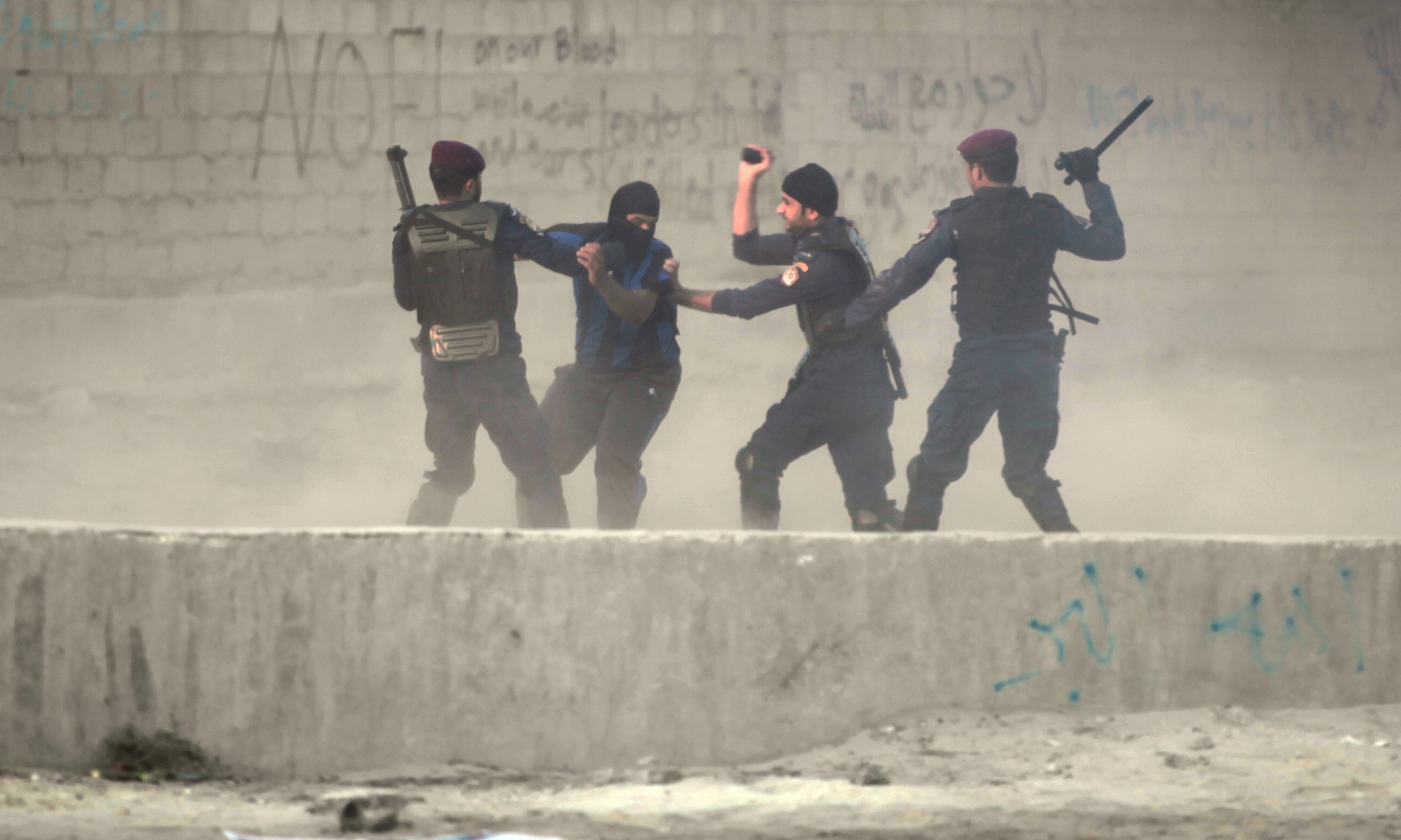 Riot police catch a Bahraini anti-government protester in the village of Shakhura on 14 August 2013