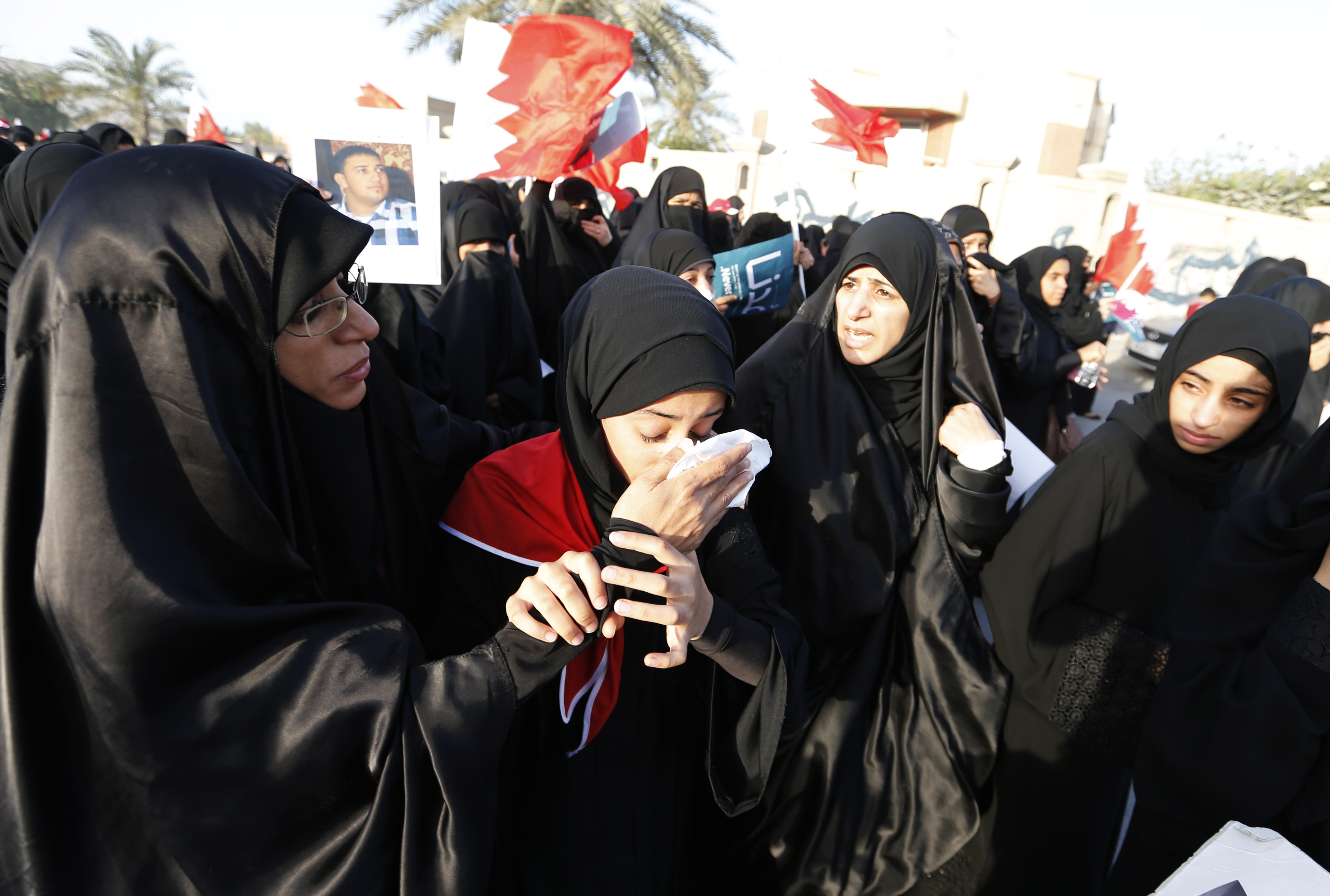 Anti-government protesters assist another protester as she reacts after inhaling tear gas fired by riot police in the village of Sanabis in Bahrain on 15 March 2013