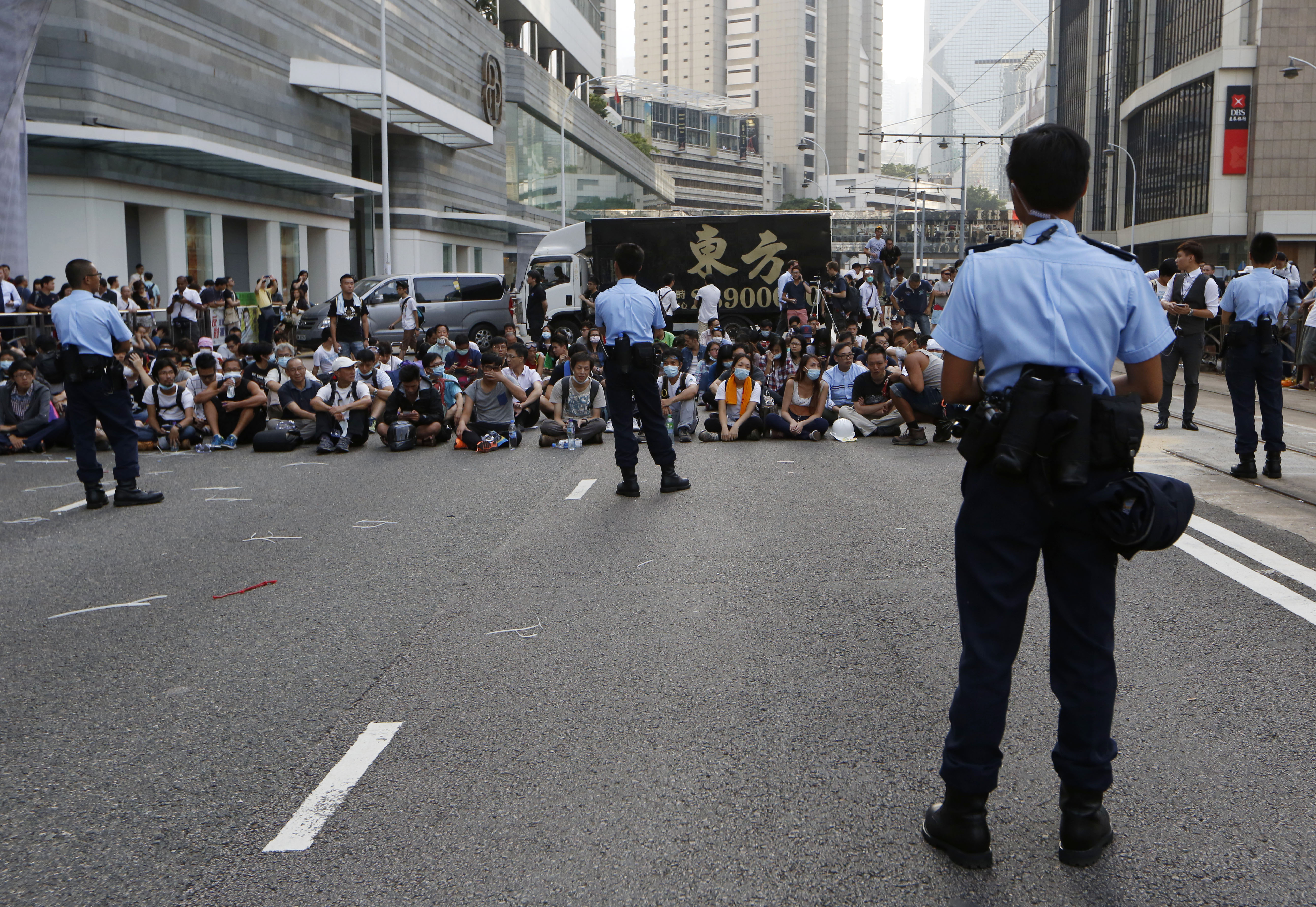 Police officers stand guard in front of pro-democracy protesters in the occupied areas outside the government headquarters in Hong Kong's Admiralty, Monday, Oct. 13, 2014.