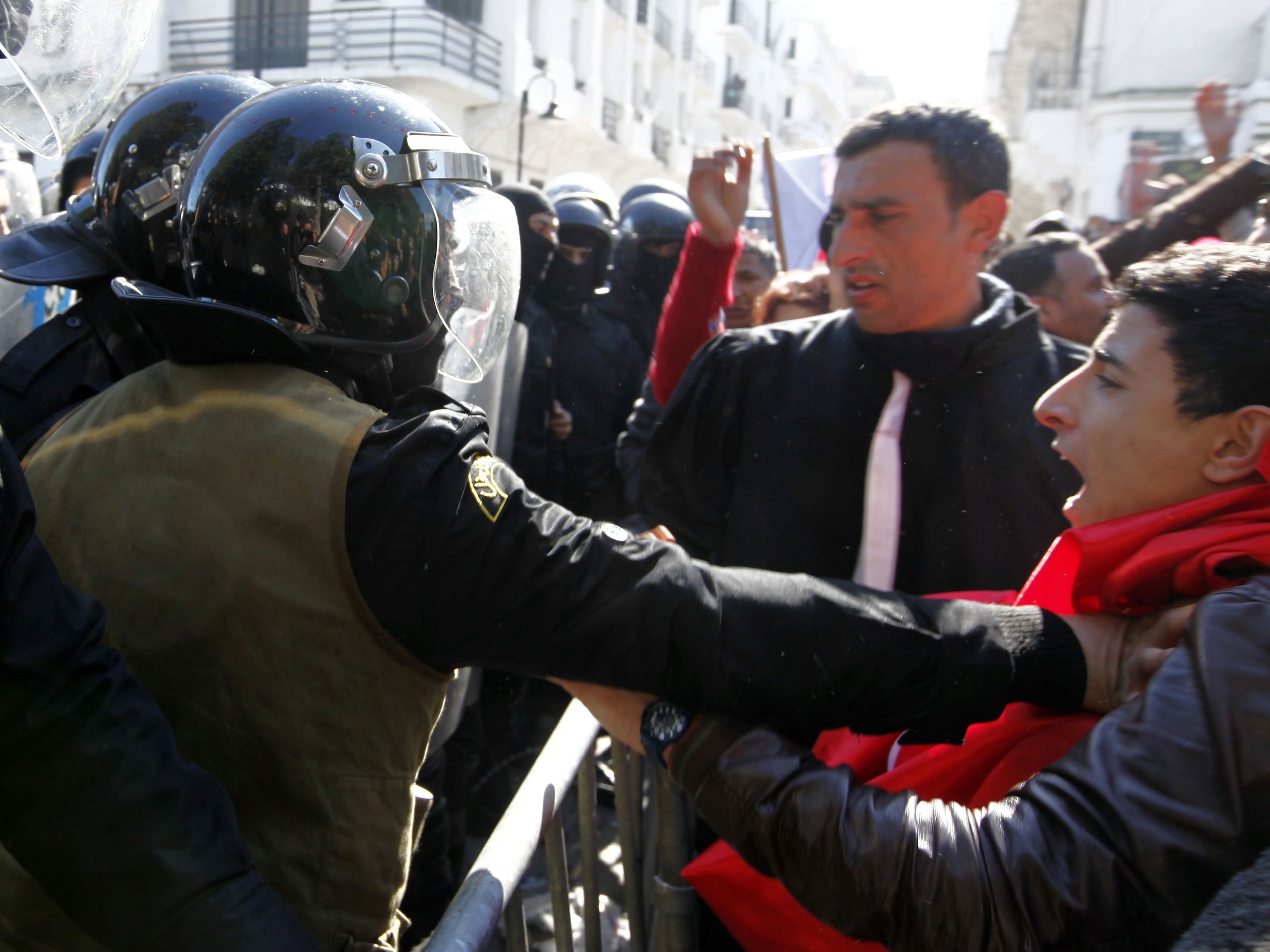 محتجون تونسيون يشتبكون مع شرطة مكافحة الشغب خلال مظاهرة بعد وفاة زعيم المعارضة التونسي شكري بلعيد، خارج وزارة الداخلية في تونس بتاريخ 6 شباط 2013