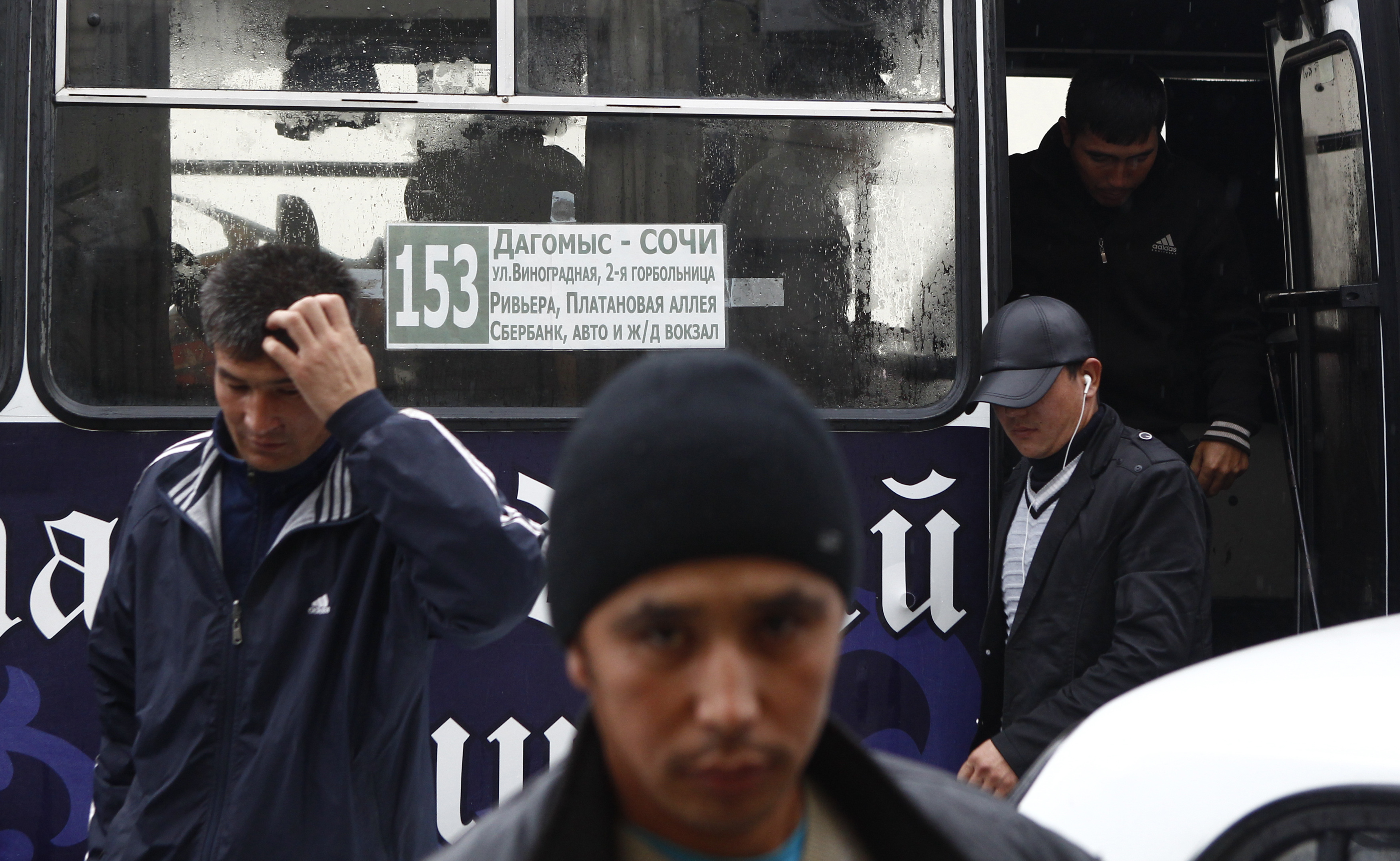 Migrant workers exit a bus after being detained in a sweep by authorities at a police station in central Sochi, 24 September 2013. 