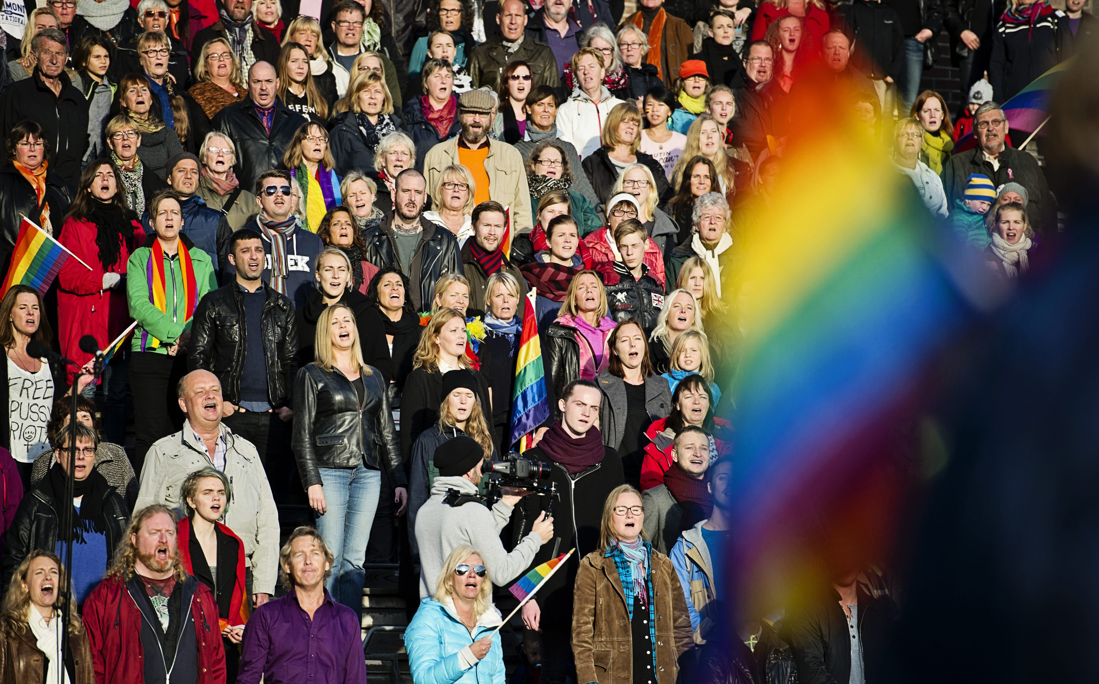 6 October 2013, Sweden. People sing the Russian national anthem while raising rainbow flags in solidarity with the Russian LGBT community at the Stockholm Olympic Stadium.