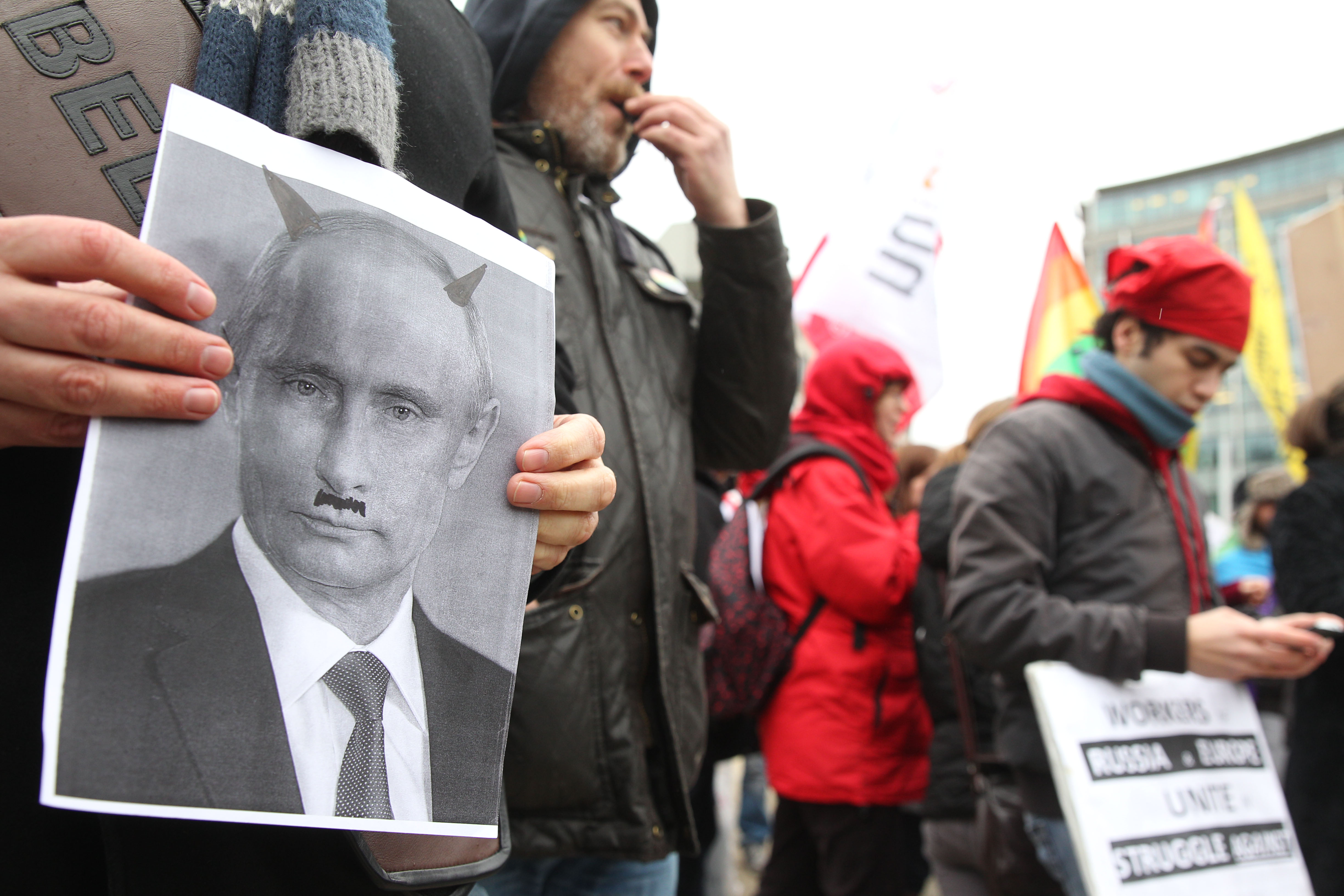 27 January 2014, Belgium. An activist shows a photo of Russia's President Vladimir Putin depicted with devil horns, as protesters gather outside the European Commission in Brussels.