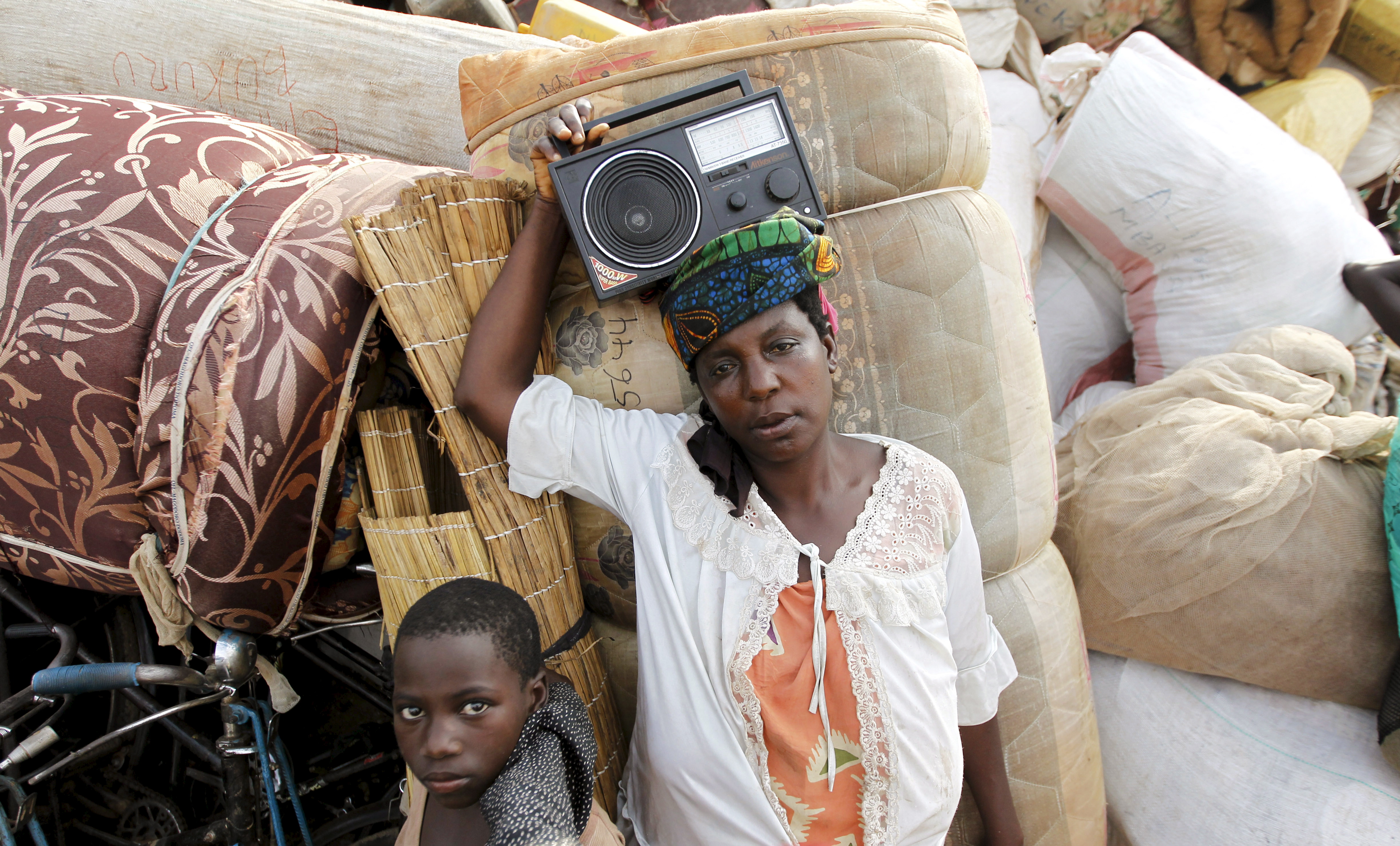 لاجئة بوروندية تحمل الراديو وهي تستريح مع أمتعتها على ضفاف بحيرة تنجانيقا في قرية كاكونغا في منطقة كيغوما غرب تنزانيا، 18 أيار 2015