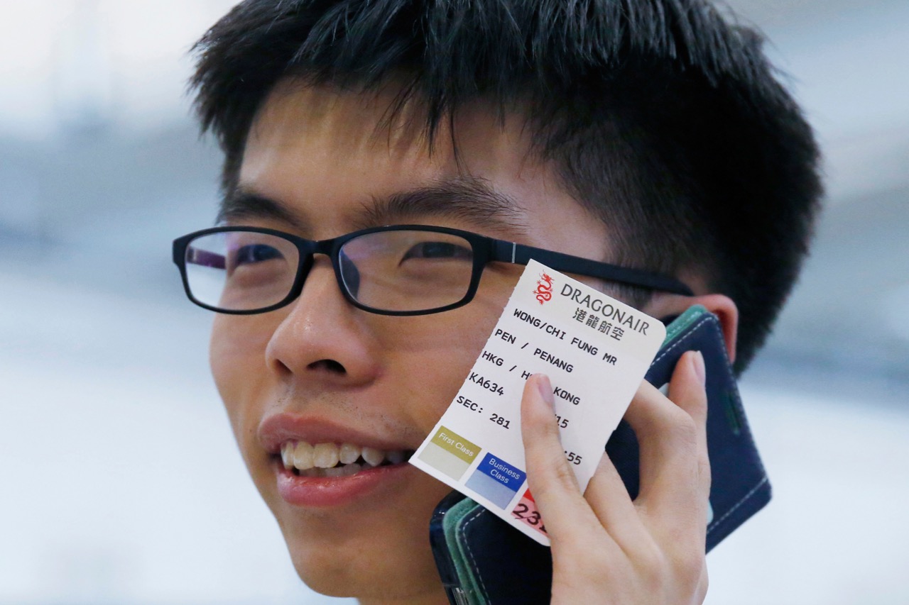 Student leader Joshua Wong talks on his mobile phone after arriving at the Hong Kong airport, 26 May 2015 
