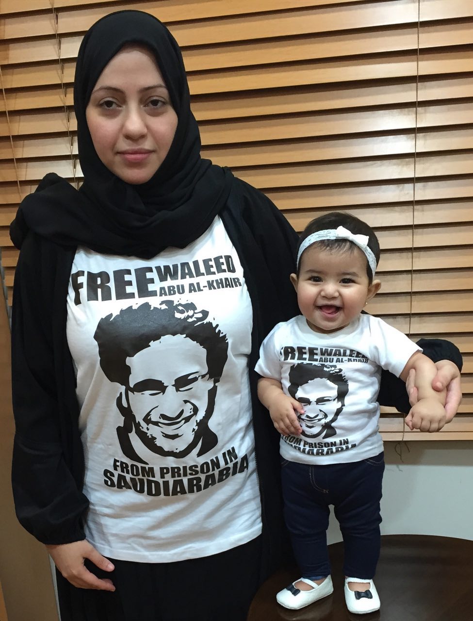 Waleed Abu al-Khair's wife Samar Badawi and their daughter Joud pose in shirts demanding his freedom